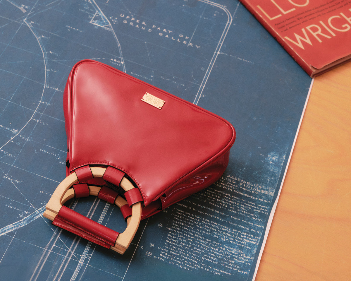 Red leather handbag with wooden handle on architectural blueprints
